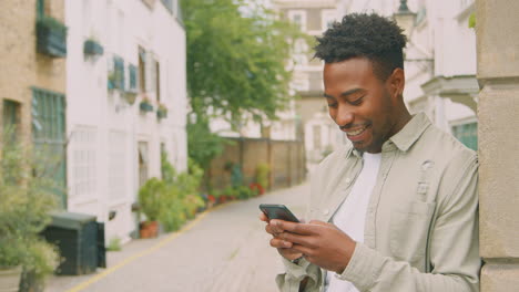 Young-Male-Vlogger-Or-Social-Influencer-Travelling-Through-City-For-Social-Media-Using-Mobile-Phone