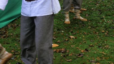 bailarines adultos con trajes folclóricos tradicionales calentándose antes de un espectáculo de danza al aire libre, noche de verano, cultura nacional letona, tiro medio de calzado simple hecho de una pieza de cuero