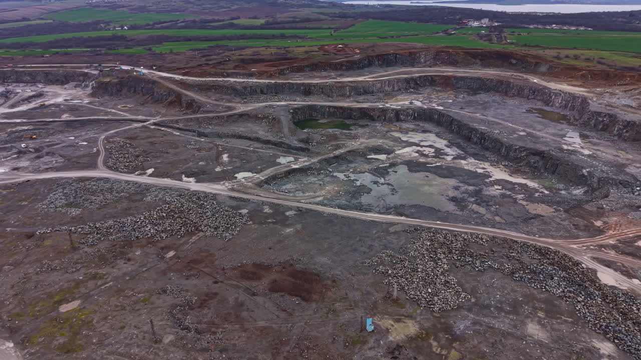 Granite quarry located near a river with large rock formations and machinery working on site during daylight hours