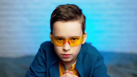 a teen boy putting on medical yellow glasses as a protection against virus disease. self isolation. covid-19 virus epidemic pandemic. social distancing.