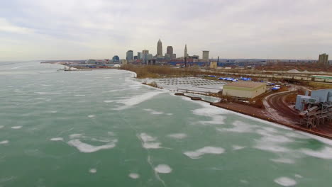 wide revealing drone shot of downtown cleveland ohio and a frozen lake erie