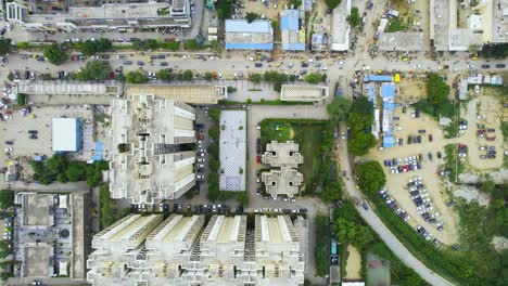 aerial drone shot looking straight down into a housing society with car parking, semi permanent buildings and open green spaces showing the rapid development of housing buildings