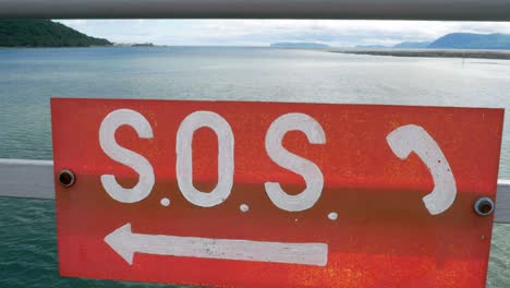 señal de sos pintada de rojo entregando las barandillas del paseo marítimo seguridad en el océano con empuje en el horizonte de la costa