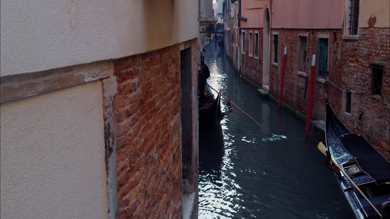 Gondoliere che conduce una gondola attraverso uno stretto canale di Venezia