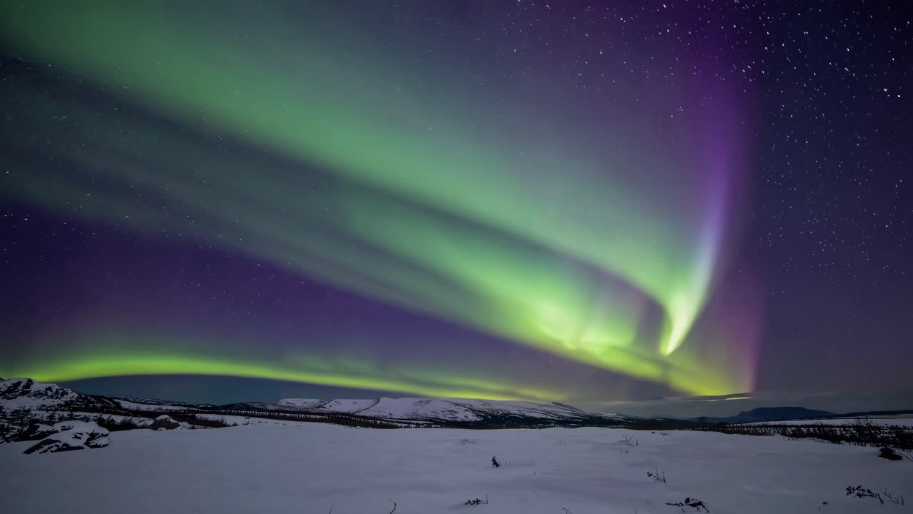 A mesmerizing wide-angle video captures the Northern Lights dancing over a snowy landscape