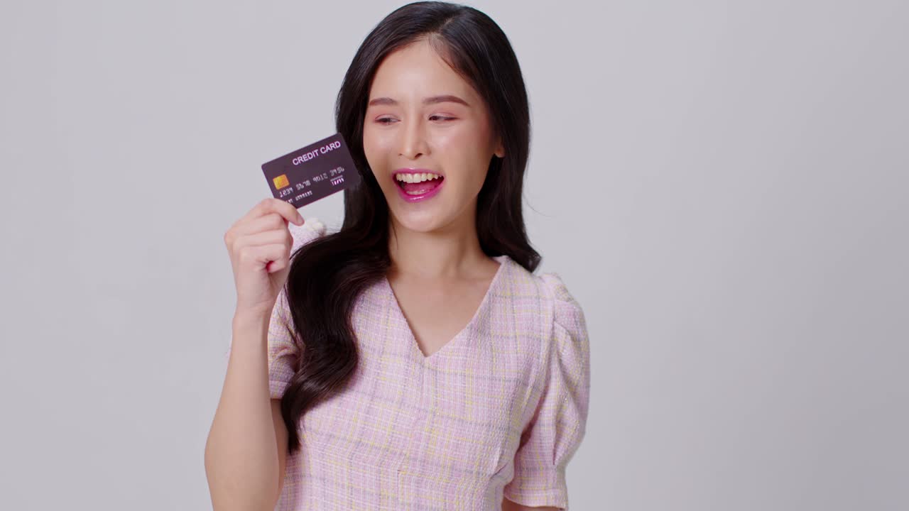 Happy attractive asian young woman hold credit card for shopping and paying smile isolated on white background.Cheerful pretty girl use banking credit card for online shopping spending bonus cashback