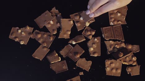 Woman-hand-takes-piece-of-chocolate-from-a-bunch-of-chocolate-pieces