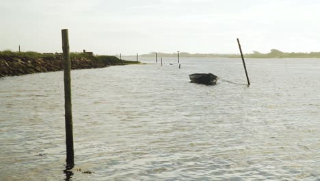 4K-silhouette-of-a-wooden-boat-Anchored-in-Ria-de-Aveiro,-old-boats-moving-on-the-river-current