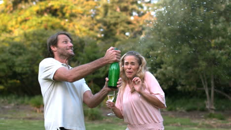 Happy-man-shaking-a-bottle-of-champagne-and-kissing-his-wife-