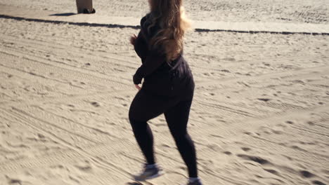 mujer independiente corriendo en la soleada playa de arena de santa monica en california