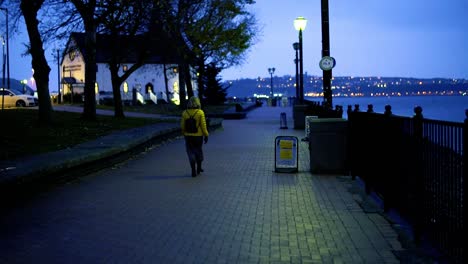 lady in yellow jacket walking by the sea on a pavement