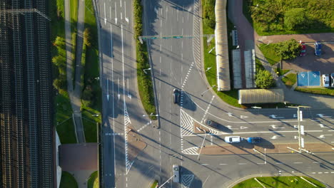 Aerial-top-down-of-cars-driving-on-main-road-beside-railway-lines-in-Gdynia-during-sunny-autumn-day