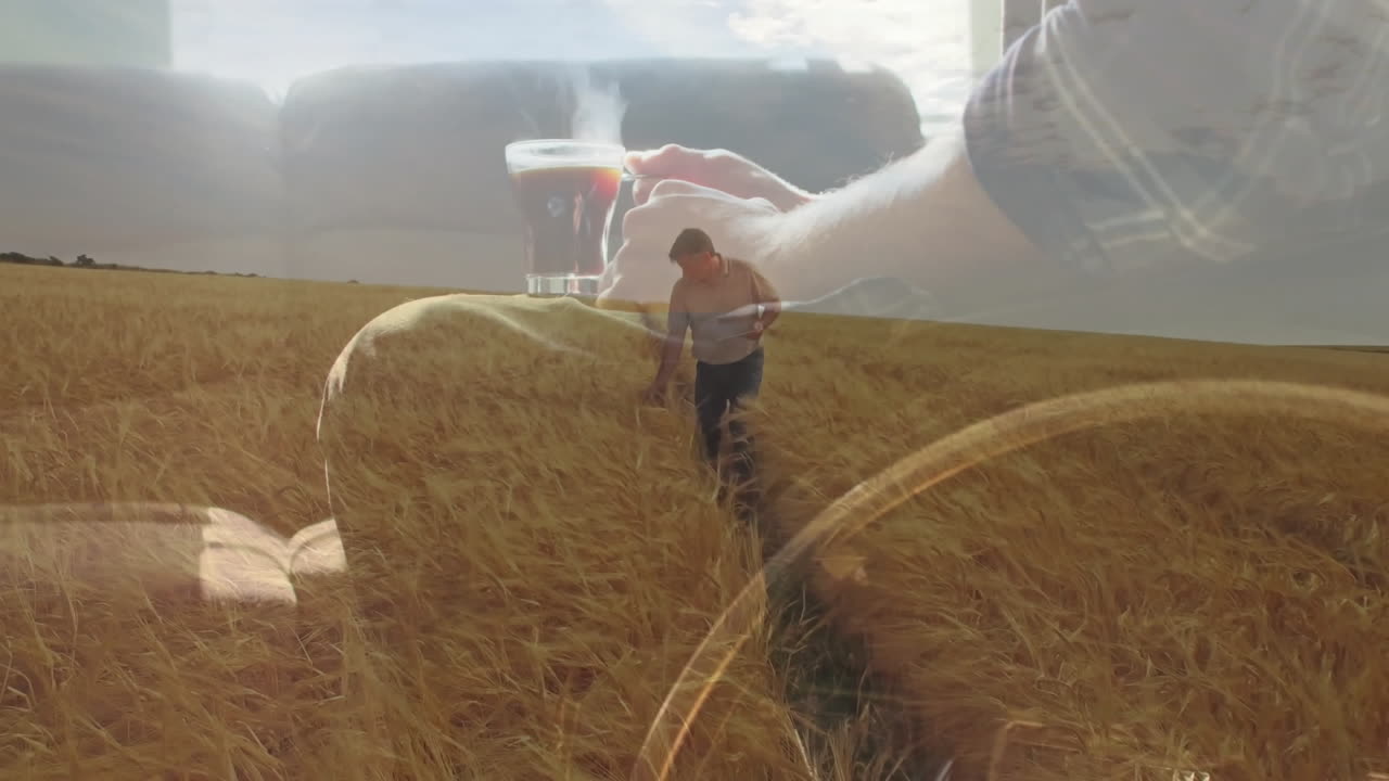 Walking through wheat field, man holding steaming coffee cup with animation overlay