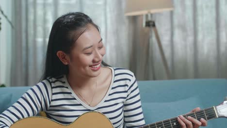 woman playing acoustic guitar at home