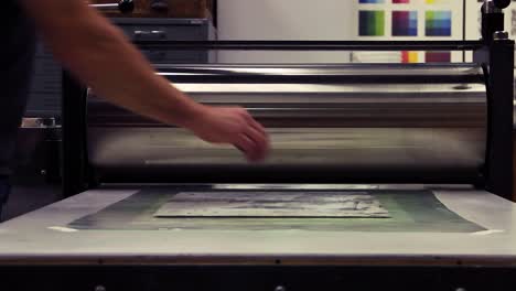 running a woodblock print through a printing press.