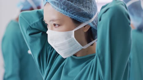 video of asian female surgeon tying face mask in operating theatre, copy space