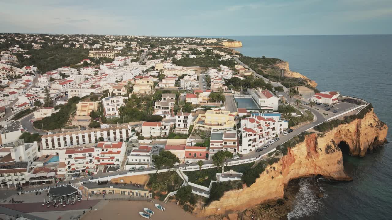 Kameraet bevæger sig fremad over det turkisblå hav og flyver mod Carvoeiros ikoniske strand, de terrasseformede klipper og de lagdelte tage i denne klassiske Algarve-kystby