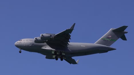 a military aircraft descends against a clear blue sky