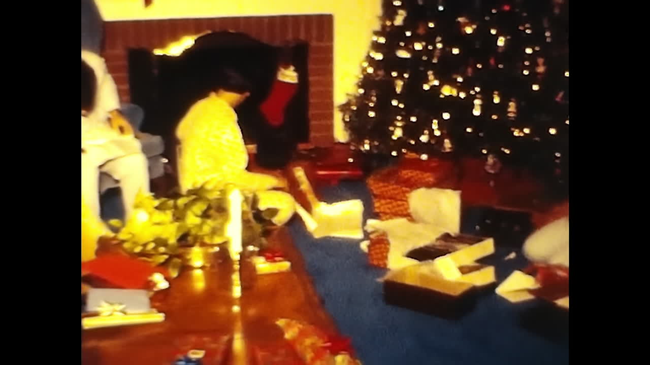 Man Sitting on Couch in Front of Christmas Tree. CIRCA USA - 1970s: A man from a 1970s video archive sits on a couch in front of a Christmas tree.