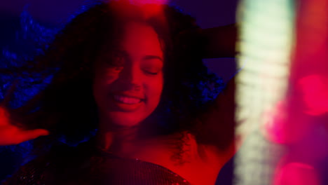 primer plano de una mujer joven en un bar nocturno o discoteca bailando con luces brillantes 1