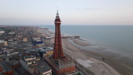 blackpool tower far slow orbit with central and south piers visible along the beach at golden hour. lancashire, uk.