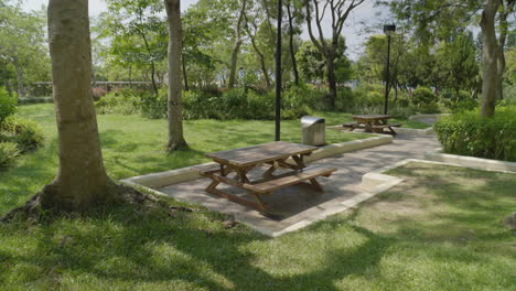 backwards panning shot of picnic park benches in calm and beautiful park in hong kong