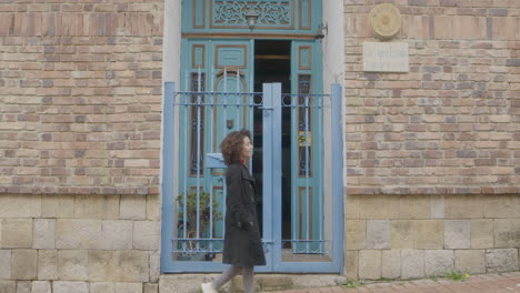 una mujer bonita camina frente al balcón azul en el contexto de viajes y descubrimientos