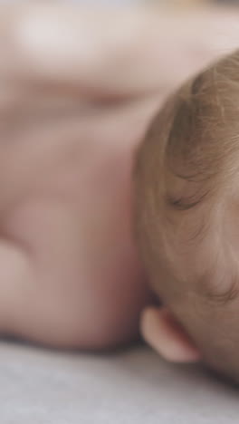 little newborn boy with blond hair lies on back and professional pediatrician practices hypertonus massage close view