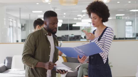 two male and female african american colleagues having business talk in office