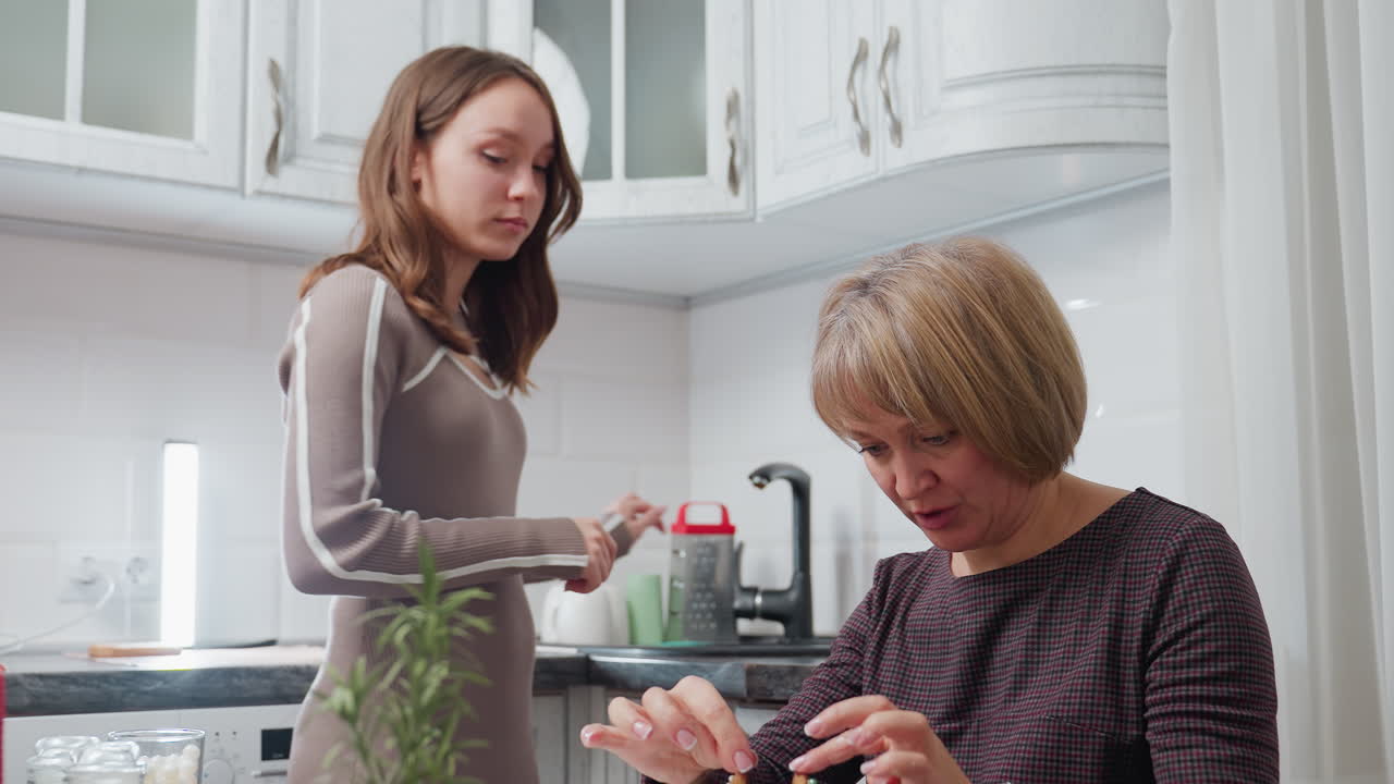 편안한 부에서 어머니와 어린 소녀가 어머니가 무언가를 조정하는 동안 상호 작용하며, 딸이 걸어서 그녀를 들고, 부드러운 배경 초점과 부 필수품이 보입니다.