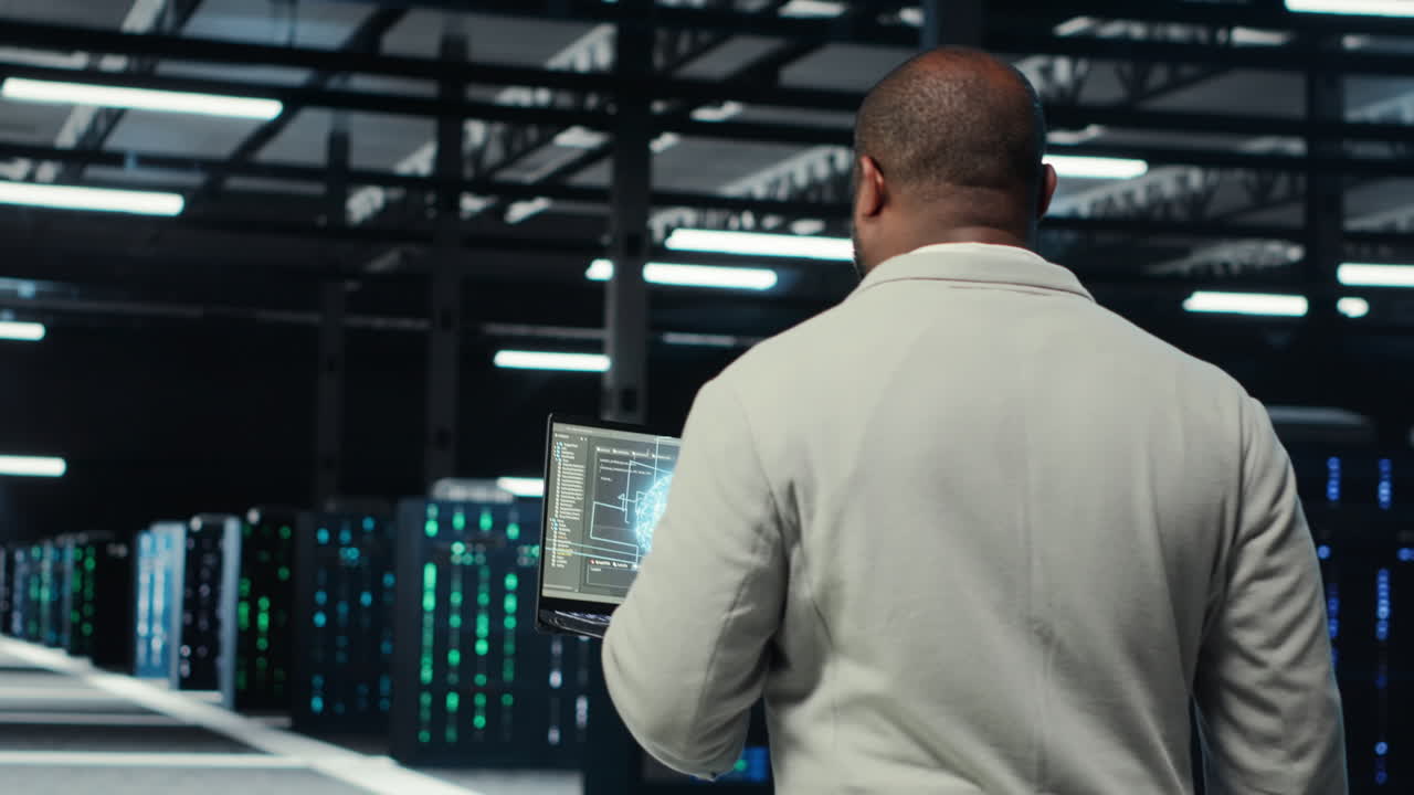 Vertical video Technician using laptop in data center, managing server virtualization