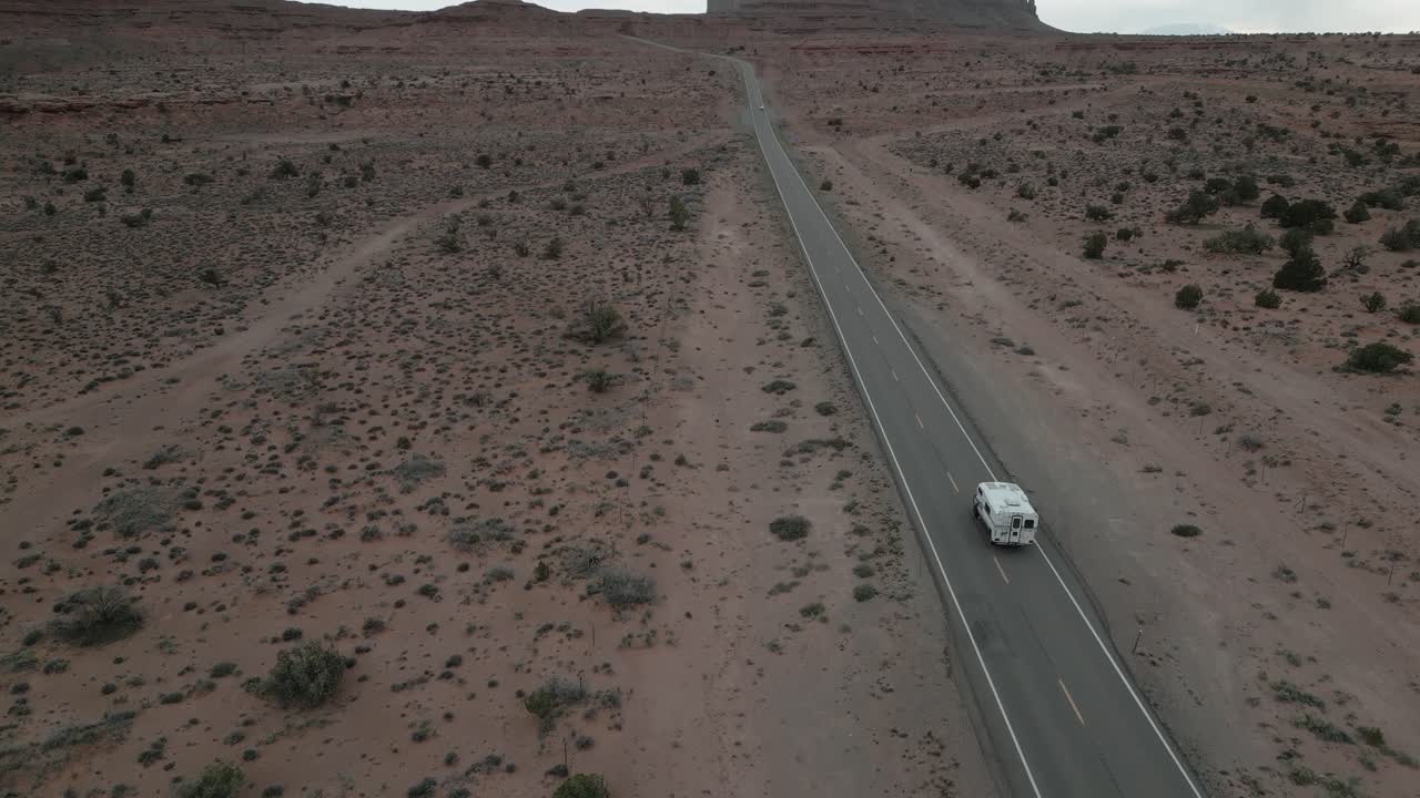 Vista aérea de uma van camper enquanto atravessa a estrada do deserto dentro do Parque Monument Valley, Utah, EUA, incorporando o espírito de van life, viagem e exploração