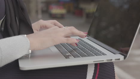 Handheld-Shot-Of-Woman-Typing-On-Laptop-Whilst-Sat-Outdoors,-In-Slowmotion---Ungraded