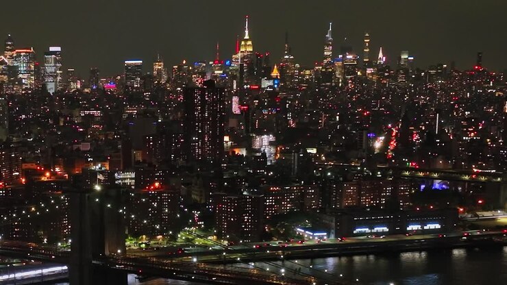 Nighttime drone view of New York City skyline with bright lights