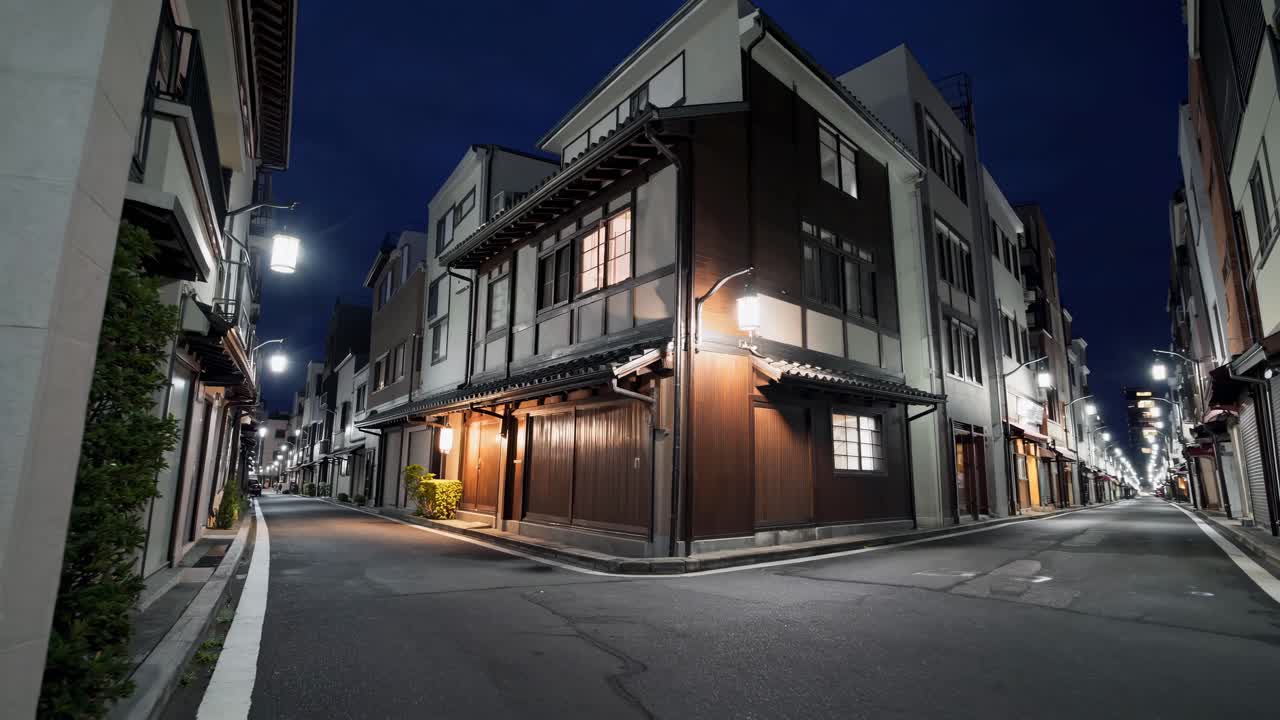 Low angle view of a narrow street with traditional Japanese houses and modern buildings glowing at night, creating a captivating blend of old and new architecture in Kyoto