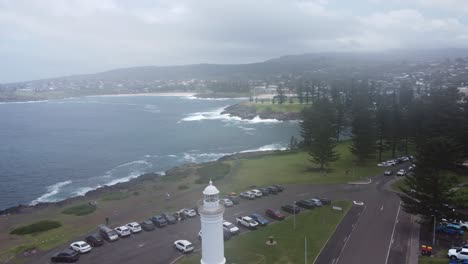 drone ascendiendo sobre un faro con un parque verde cerca de