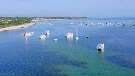 Flying-Over-Caribbean-Sea-With-Boats-In-Bavaro,-Punta-Cana,-Dominican-Republic---aerial-drone-shot