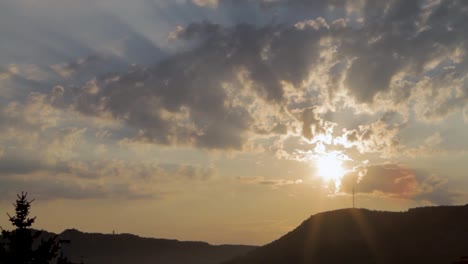 light rays behind sky with clouds, beautiful golden sunset, mountain range, hill