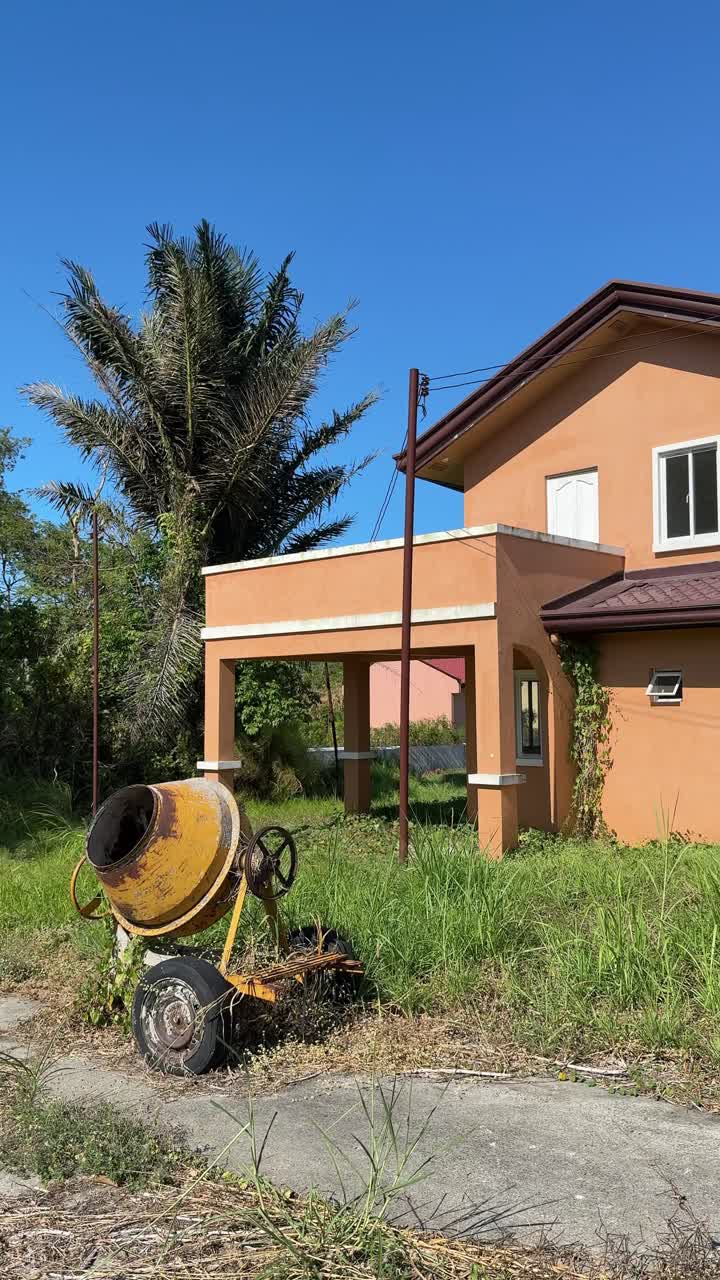 Pemandangan dari permukaan tanah sebuah rumah kosong dengan cat mengelupas dan retakan yang terlihat di seluruh dinding luar.