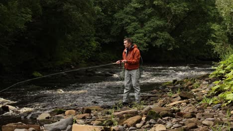 wide angle shot of a flyfisherman walking and casting into a quick moving stream