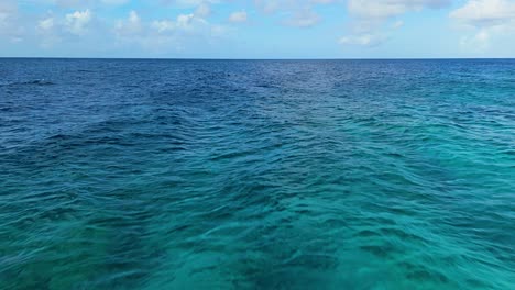 Aerial-dolly-above-sandy-reef-below-clear-dark-blue-turquoise-Caribbean-water