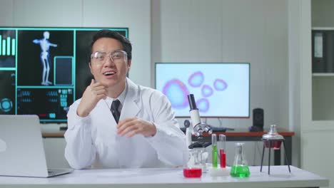 asian scientist researching in the laboratory with a microscope and speaking to the camera