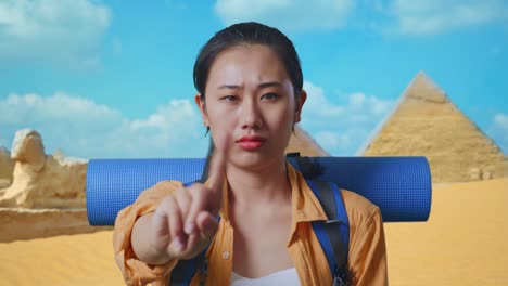 close up of asian female hiker with mountaineering backpack showing no gesture with index finger while traveling in pyramid of giza
