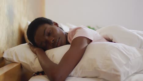 mujer afroamericana durmiendo y usando pijama blanco en su dormitorio