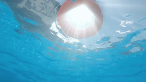 life buoy floating in a swimming pool with sun rays shining, slow motion, underwater view