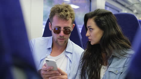 en un tren mirando a una pareja de teléfonos