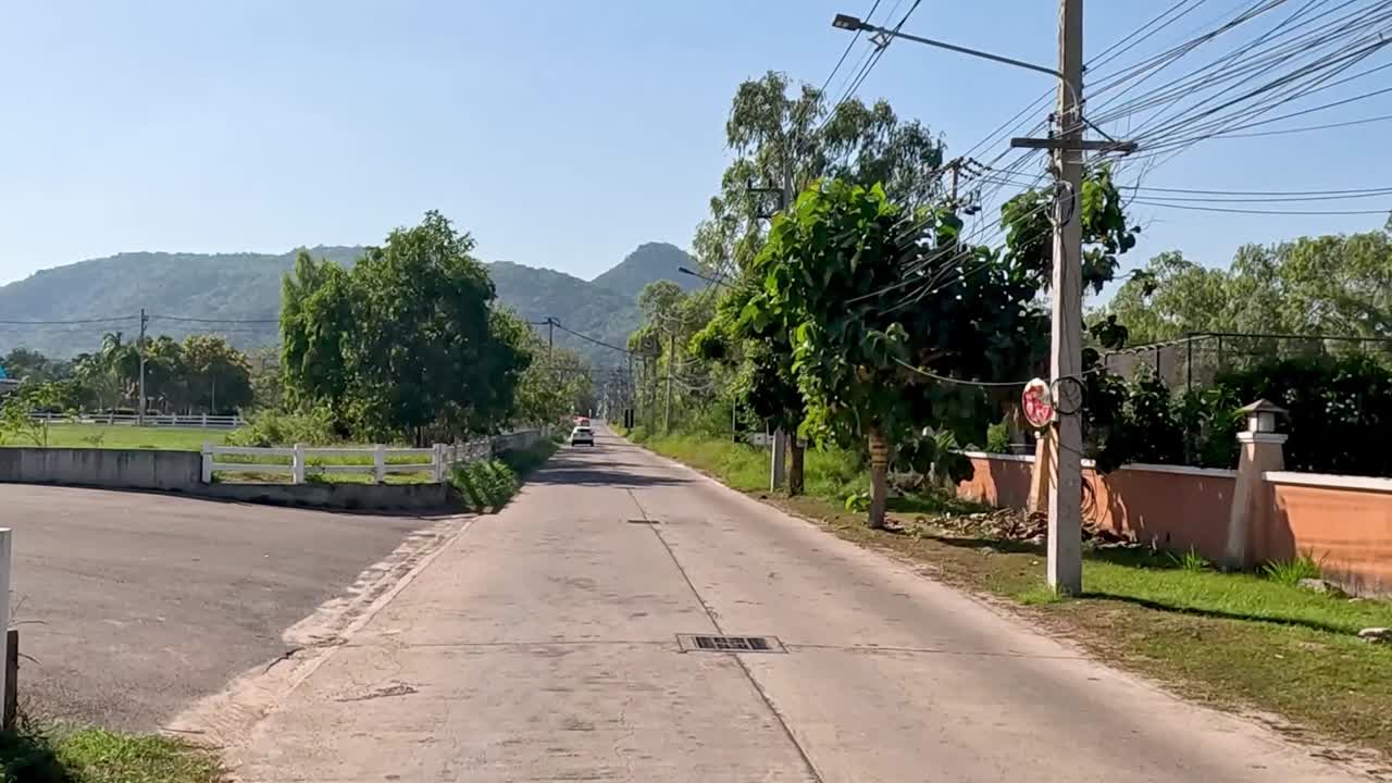 A peaceful drive showcasing lush greenery, distant hills, and clear skies along a rural road.