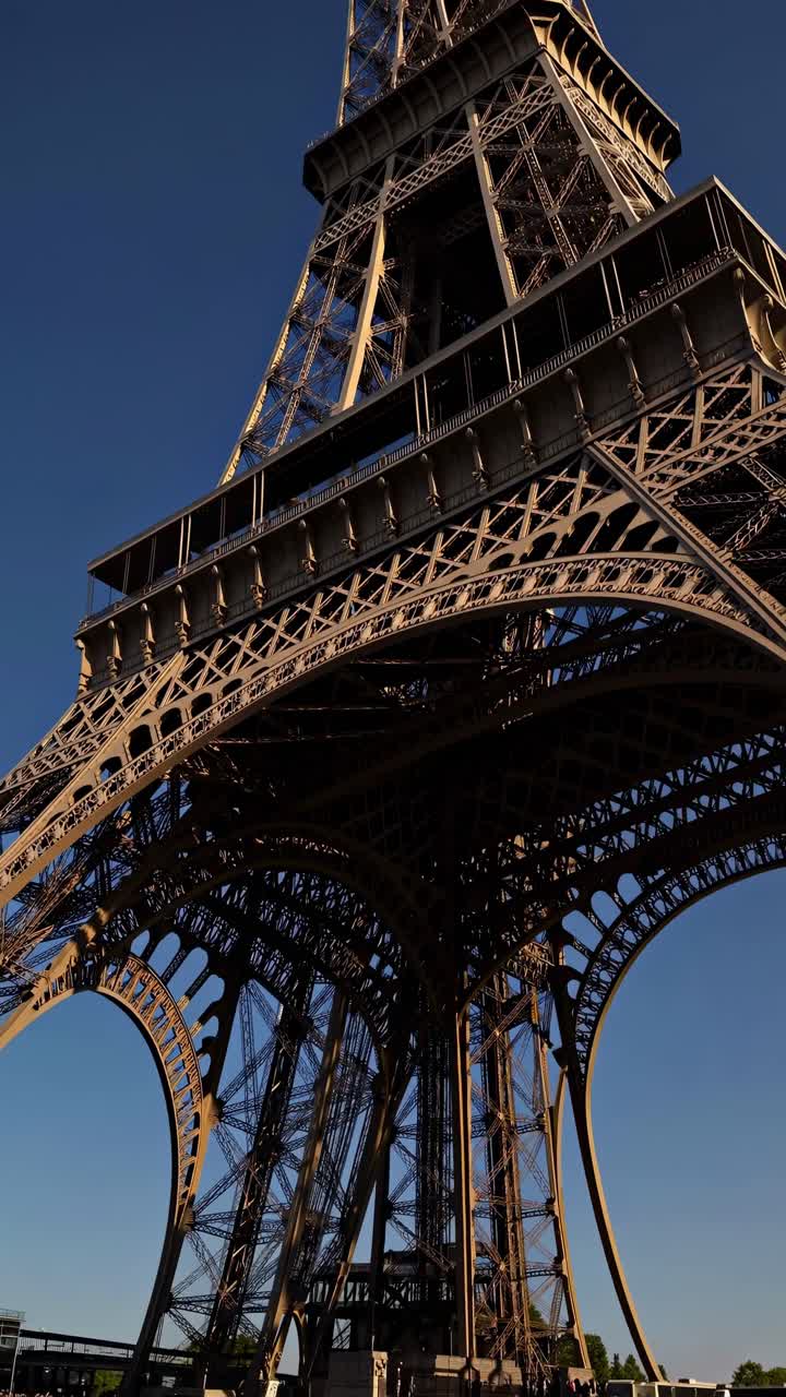 Low-angle video shot of the Eiffel Tower, capturing its intricate ironwork against a clear blue sky