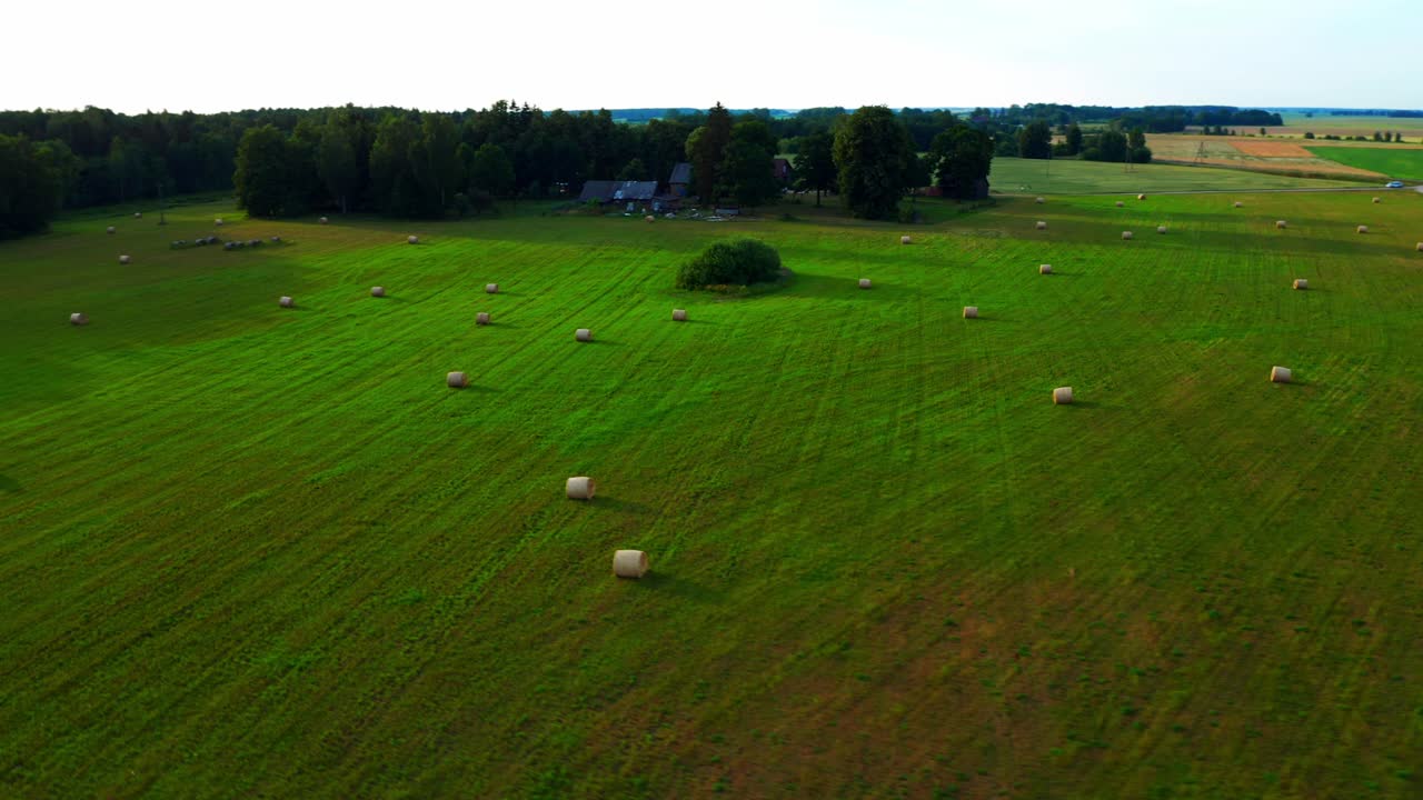 Panoramica aerea laterale su terreni agricoli con rotoballe sul campo