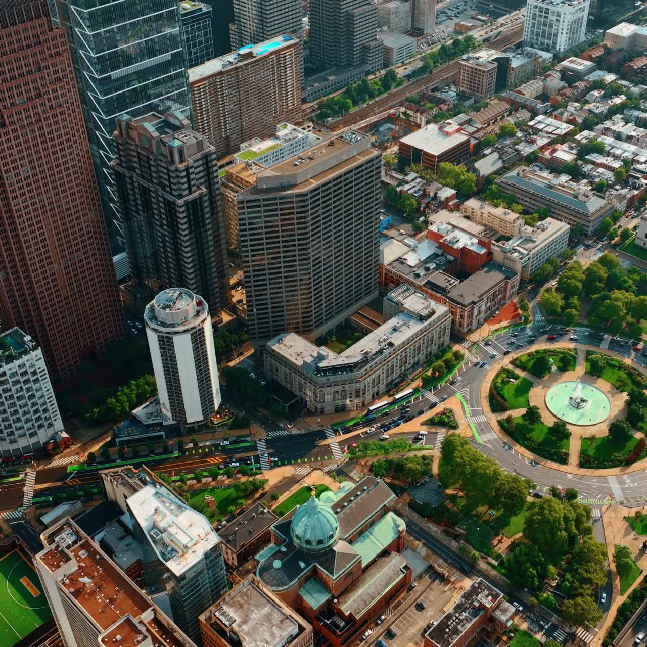 Cars run by the roundabout and by the highway near the beautiful skyscrapers in Philadelphia. Sunny view of the city in Pennsylvania State, US. Top view